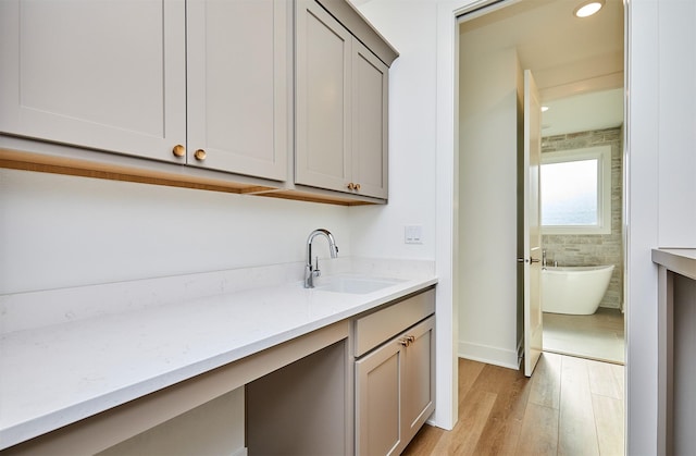 laundry room with recessed lighting, a sink, and light wood-style floors