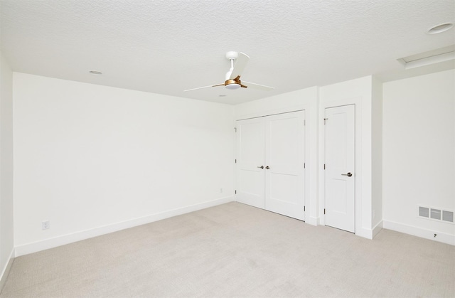 unfurnished bedroom featuring ceiling fan, a textured ceiling, light carpet, visible vents, and baseboards