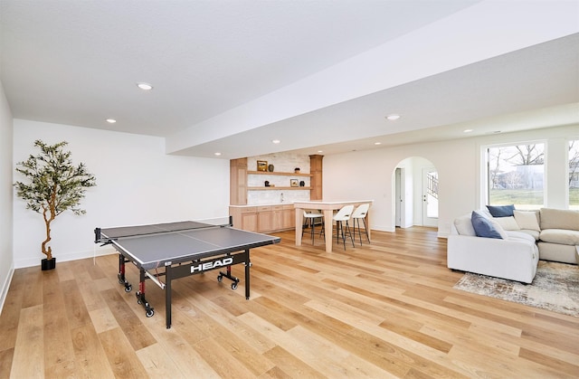 playroom with light wood-style flooring, arched walkways, indoor bar, and recessed lighting