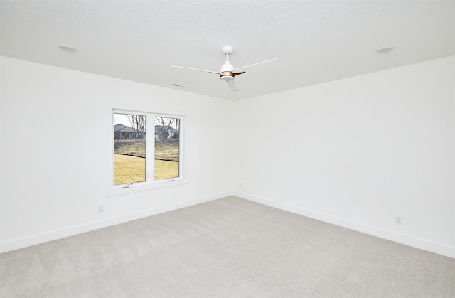 spare room with light carpet, a textured ceiling, and baseboards