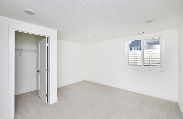 unfurnished bedroom with baseboards, visible vents, a textured ceiling, and light colored carpet