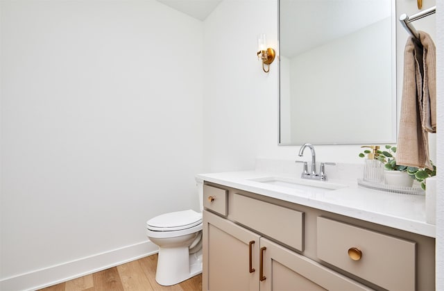 bathroom featuring baseboards, vanity, toilet, and wood finished floors