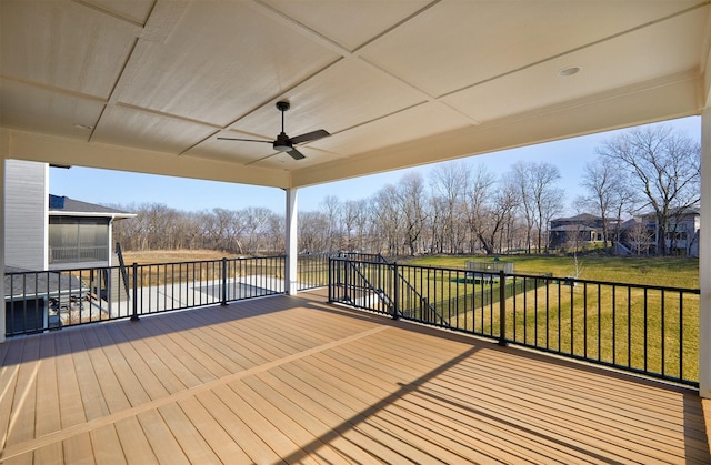 wooden terrace with a ceiling fan and a yard