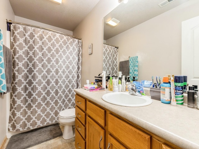 bathroom with a textured ceiling, vanity, and toilet