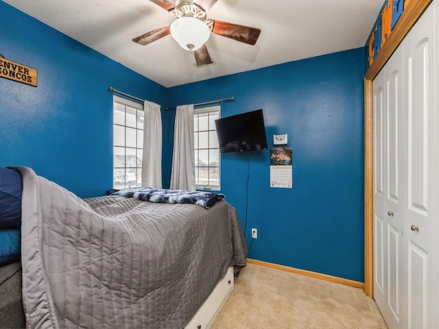 bedroom with ceiling fan, light colored carpet, and a closet