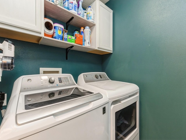 clothes washing area featuring separate washer and dryer and cabinets