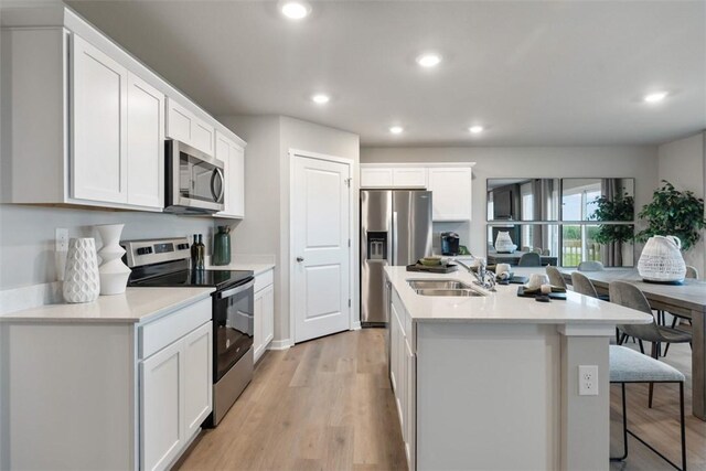 4408 NE 11th St, Ankeny, IA 50021 - kitchen featuring appliances with stainless steel finishes, an island with sink, recessed lighting, light wood-type flooring, and white cabinets