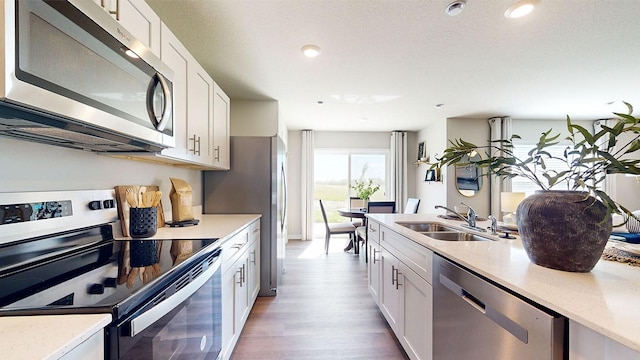 1155 Magnolia Ln, Waukee, IA 50263 - kitchen with stainless steel appliances, wood finished floors, white cabinetry, light stone counters, and recessed lighting
