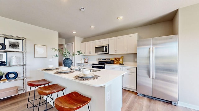 1161 Magnolia Ln, Waukee, IA 50263 - kitchen featuring stainless steel appliances, light wood-style floors, white cabinets, light countertops, and an island with sink