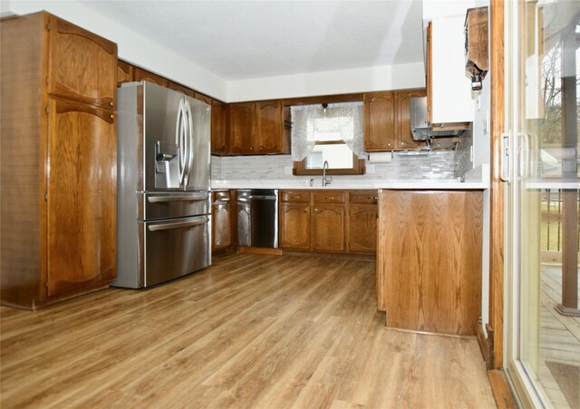 kitchen featuring decorative backsplash, light wood-type flooring, sink, and appliances with stainless steel finishes