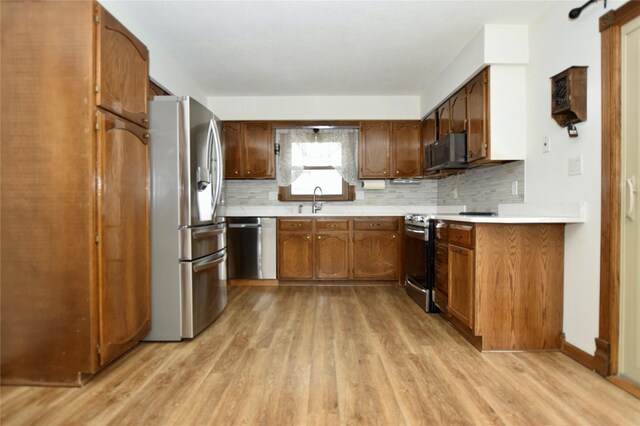 kitchen with light hardwood / wood-style floors, sink, appliances with stainless steel finishes, and tasteful backsplash