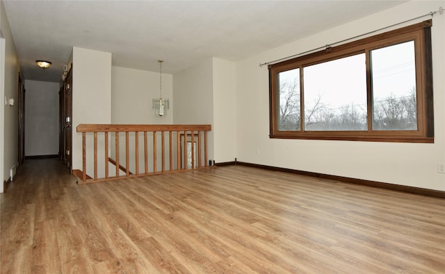 empty room with light hardwood / wood-style floors and a notable chandelier