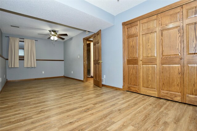 unfurnished bedroom with a textured ceiling, light wood-type flooring, and ceiling fan