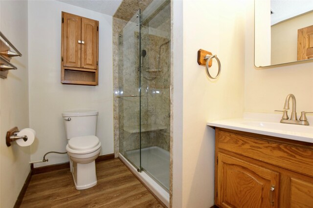 bathroom with wood-type flooring, vanity, a shower with shower door, and toilet