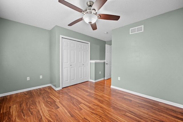 unfurnished bedroom featuring hardwood / wood-style flooring, a closet, and ceiling fan