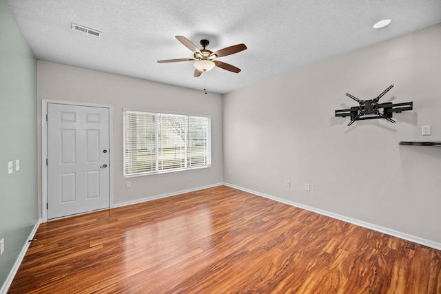 empty room with ceiling fan, hardwood / wood-style flooring, and a textured ceiling