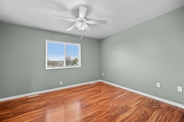 empty room with ceiling fan, hardwood / wood-style floors, and a textured ceiling