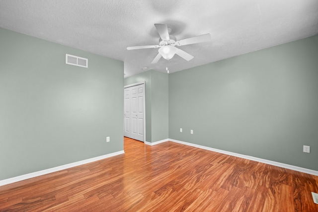 unfurnished room with hardwood / wood-style flooring, ceiling fan, and a textured ceiling