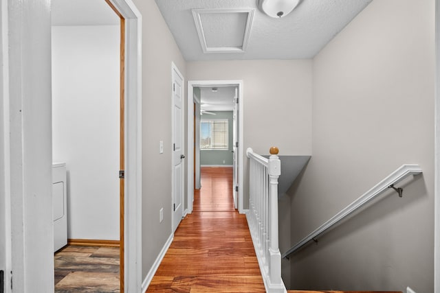 hall featuring washer / clothes dryer, hardwood / wood-style floors, and a textured ceiling