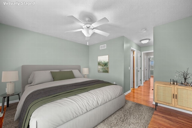 bedroom featuring ceiling fan, hardwood / wood-style floors, and a textured ceiling