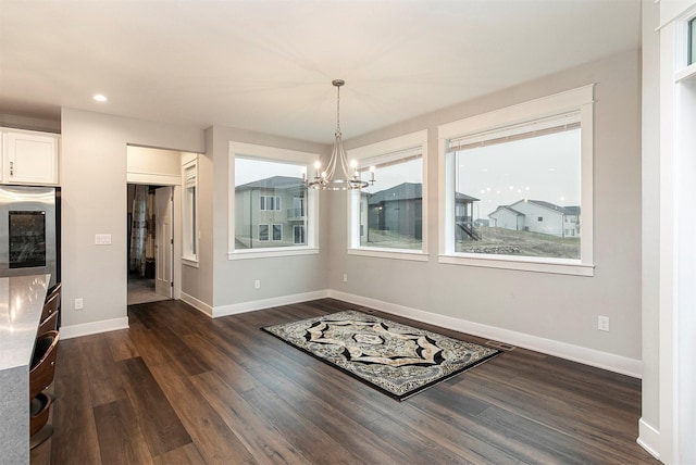 unfurnished dining area featuring a chandelier and dark wood-type flooring