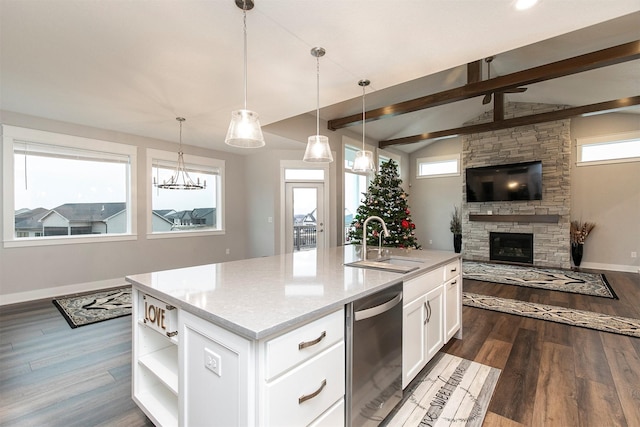 kitchen with a kitchen island with sink, sink, decorative light fixtures, dishwasher, and a stone fireplace