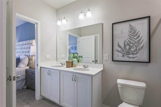 bathroom with toilet, vanity, and tile patterned flooring