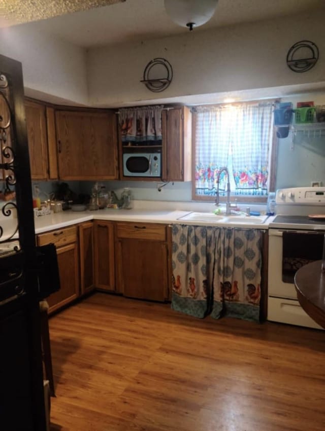 kitchen with sink, light hardwood / wood-style floors, and white appliances