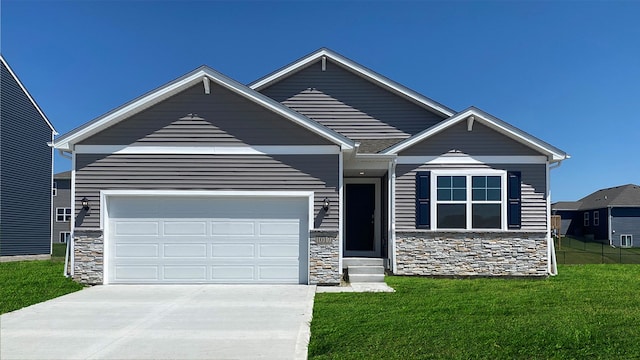 craftsman inspired home with a front lawn, an attached garage, stone siding, and driveway