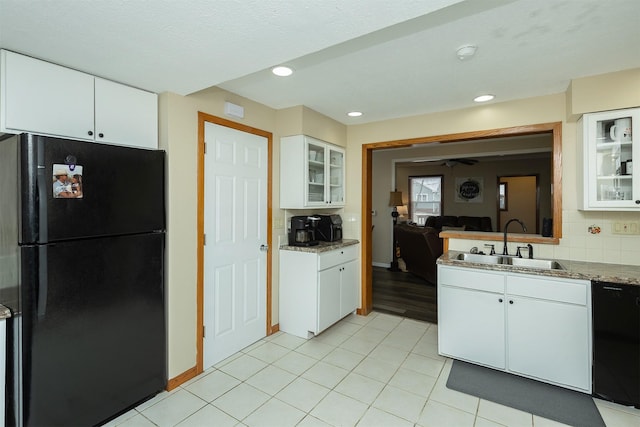 kitchen featuring backsplash, black appliances, sink, light stone counters, and white cabinetry