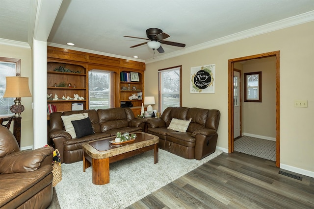 living room with ceiling fan, dark hardwood / wood-style flooring, built in features, and crown molding