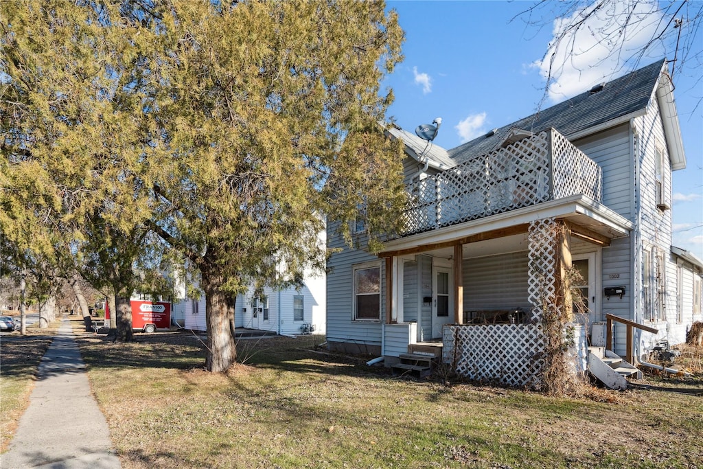 view of front facade with covered porch, a balcony, and a front yard