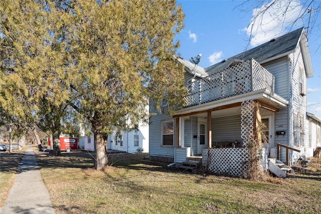 view of front facade with covered porch, a balcony, and a front yard