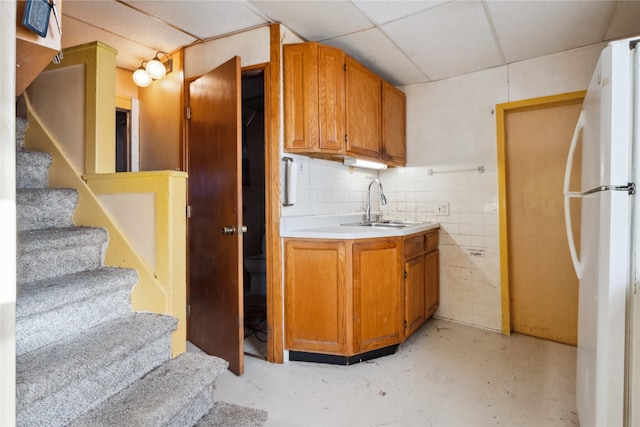 kitchen featuring white refrigerator, a paneled ceiling, and sink