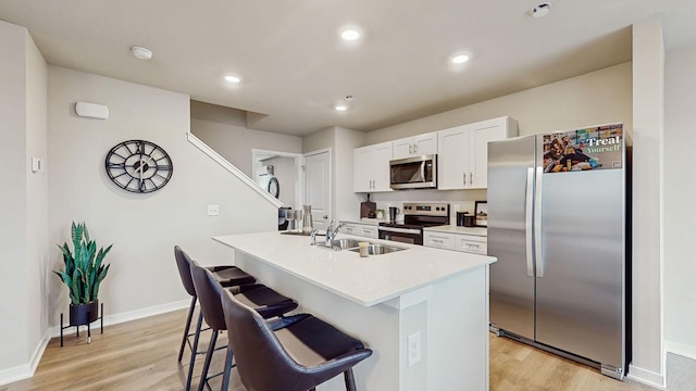 kitchen with white cabinetry, an island with sink, a breakfast bar area, stainless steel appliances, and sink