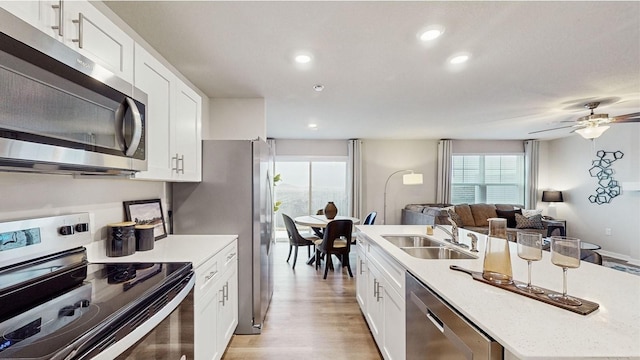 kitchen with ceiling fan, stainless steel appliances, white cabinets, light hardwood / wood-style flooring, and sink