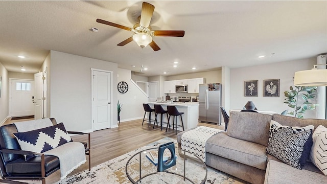 living room with ceiling fan and light hardwood / wood-style floors