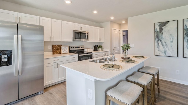 kitchen with sink, light hardwood / wood-style flooring, white cabinetry, a kitchen island with sink, and stainless steel appliances