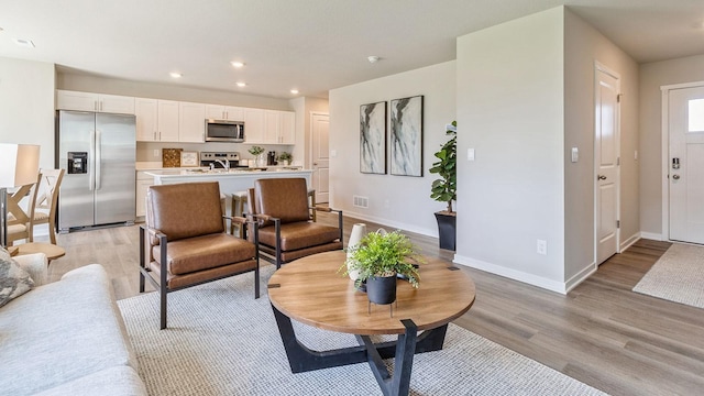 living room with baseboards, visible vents, light wood-style flooring, and recessed lighting