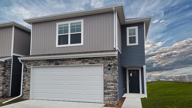 view of front of home featuring a garage, stone siding, driveway, and a front lawn