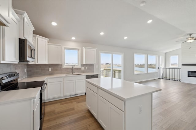 kitchen with appliances with stainless steel finishes, backsplash, light wood-type flooring, and a sink