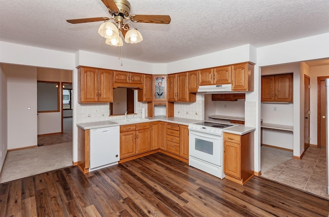 kitchen featuring dark wood-type flooring, backsplash, and white appliances