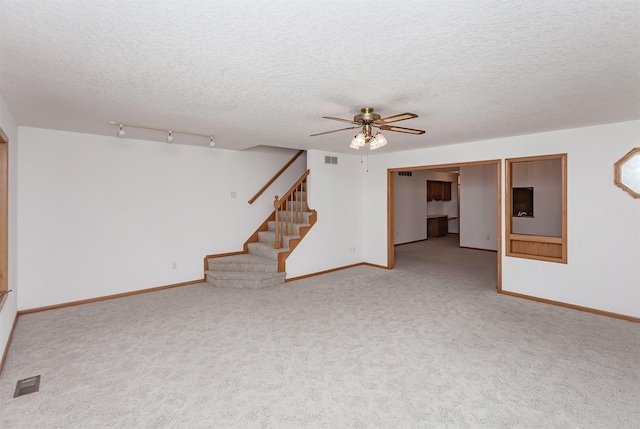 unfurnished living room featuring rail lighting, carpet floors, and a textured ceiling