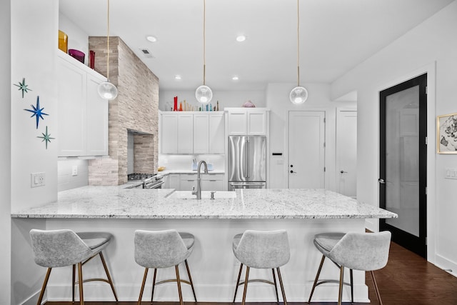 kitchen featuring sink, hanging light fixtures, kitchen peninsula, white cabinets, and appliances with stainless steel finishes