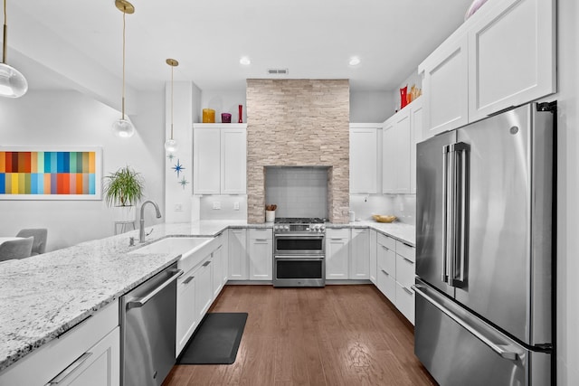 kitchen with appliances with stainless steel finishes, backsplash, sink, decorative light fixtures, and white cabinetry