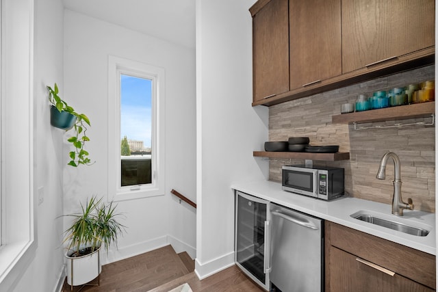 kitchen featuring sink, beverage cooler, stainless steel appliances, dark hardwood / wood-style floors, and decorative backsplash