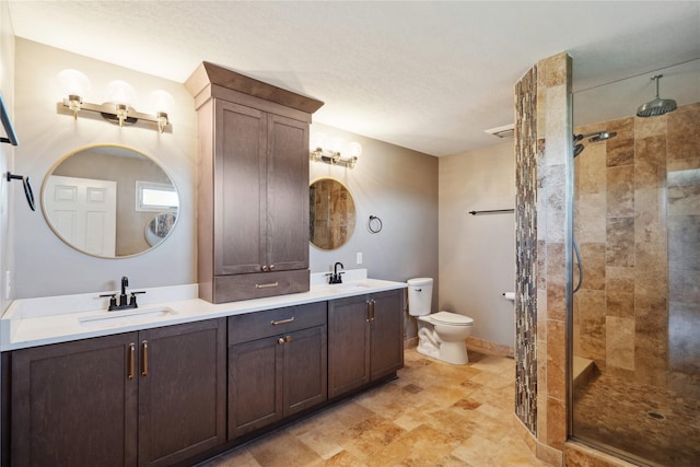 bathroom featuring tiled shower, vanity, and toilet