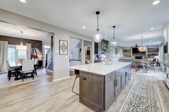 kitchen featuring a center island, decorative light fixtures, light stone counters, and light hardwood / wood-style floors