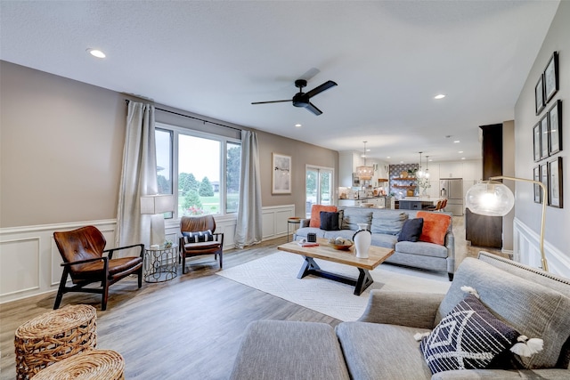 living room with light hardwood / wood-style flooring and ceiling fan