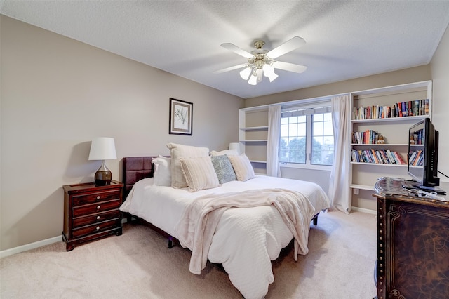 bedroom featuring ceiling fan, light carpet, and a textured ceiling